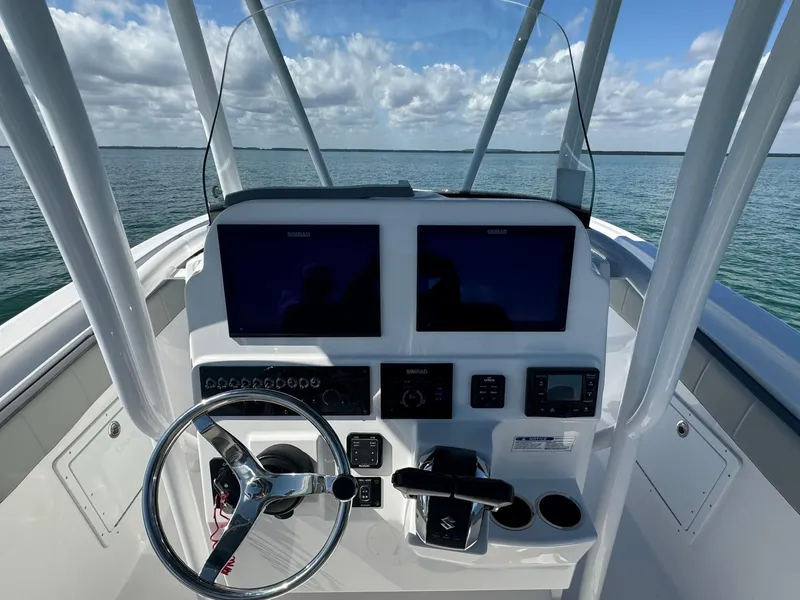 Slide: The Image of 2022 Aquasport 2500 Center Console boat dashboard with dual screens and steering wheel. - 23