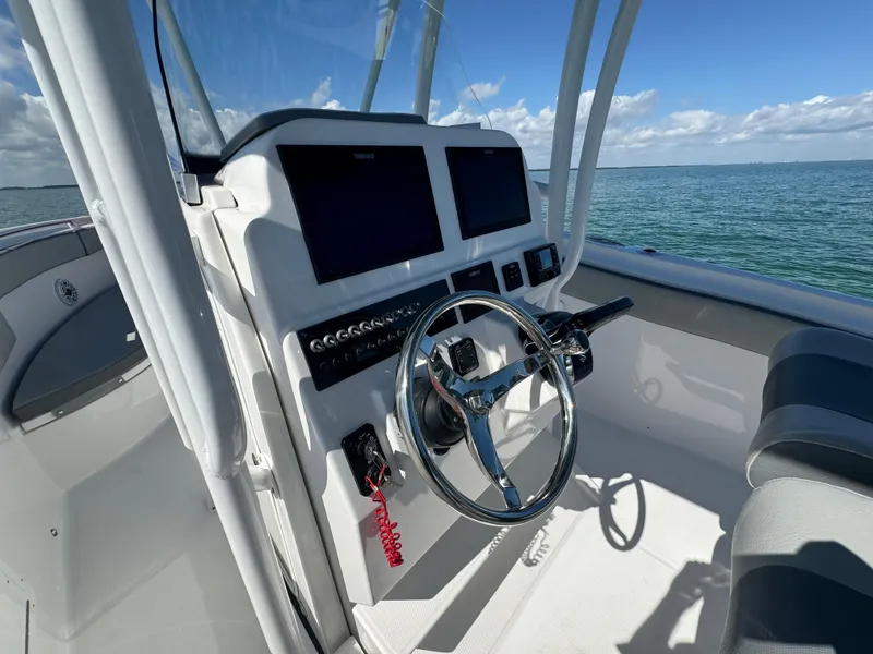 Slide: The Image of 2022 Aquasport 2500 Center Console boat helm with dual screens and ocean view. - 29