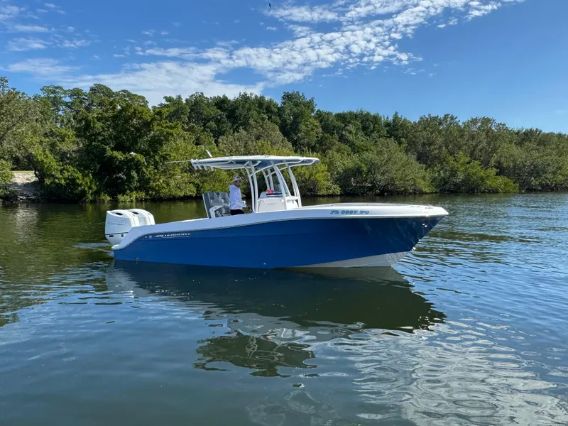 Slide: The Image of 2022 Aquasport 2500 Center Console boat on calm water near lush greenery. - 4