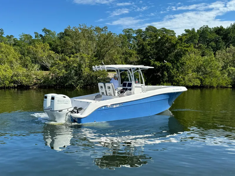 Slide: The Image of 2022 Aquasport 2500 Center Console boat on calm water with lush greenery. - 6