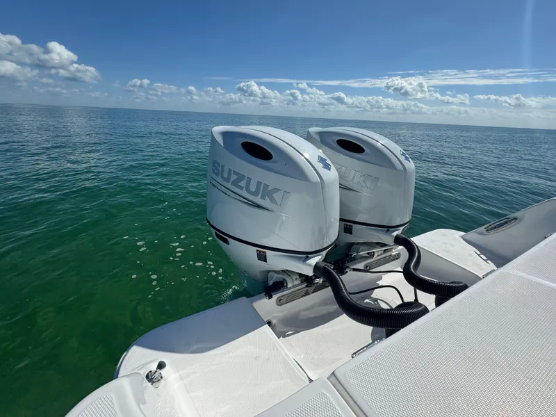Slide: The Image of 2022 Aquasport 2500 Center Console with twin Suzuki outboard motors on open water. - 8