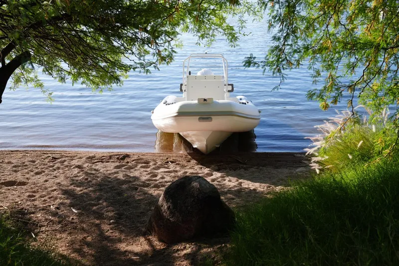 Slide: The Image of Tide Craft Sanibel 17 boat on a serene lakeside, surrounded by lush greenery, 2026 model. - 6