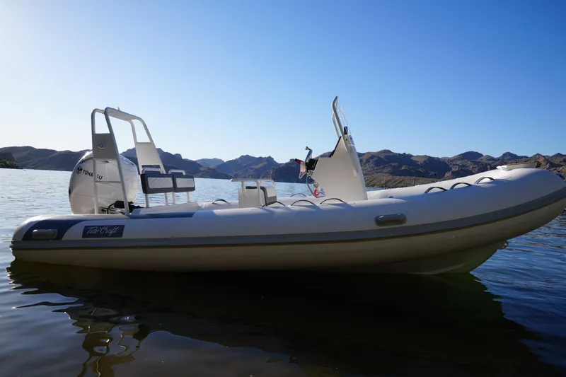 Slide: The Image of 2026 Tide Craft Sanibel 17 boat on calm water with mountainous backdrop. - 9