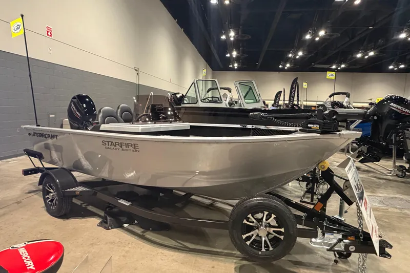 The Image of 2026 Starcraft Starfire 160 SC boat displayed indoors on a trailer. - 1