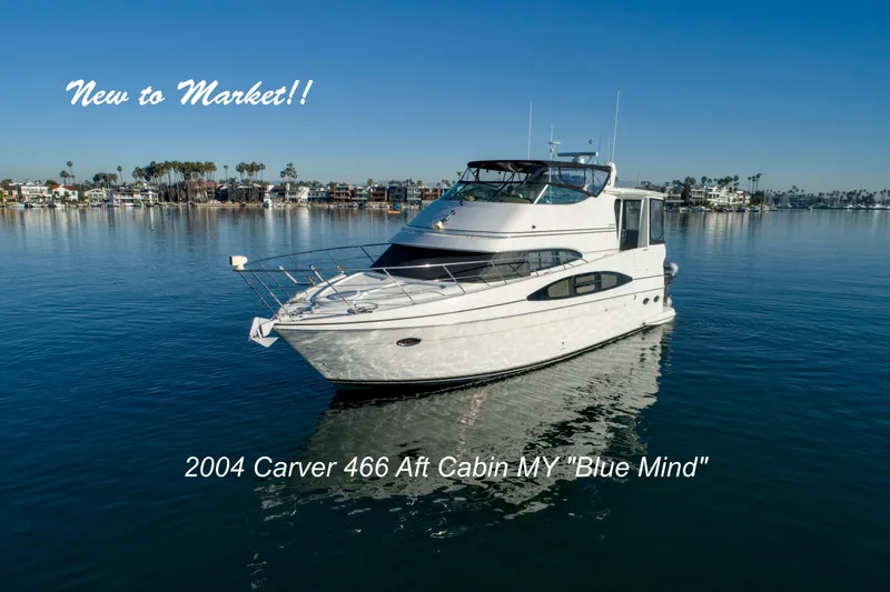 Slide: The Image of 2004 Carver 466 Motor Yacht on calm water, with coastal homes in the background. - 1