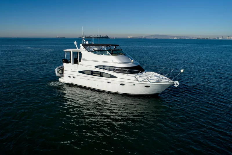 Slide: The Image of 2004 Carver 466 Motor Yacht with sun lounge, docked in marina under clear blue sky. - 3