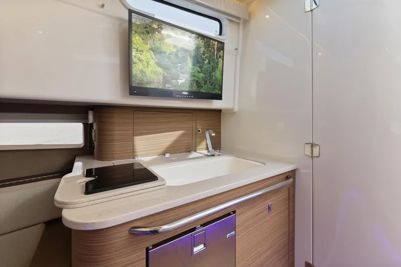 Slide: The Image of Luxurious interior of 2018 Boston Whaler 420 Outrage with modern kitchenette and TV. - 38