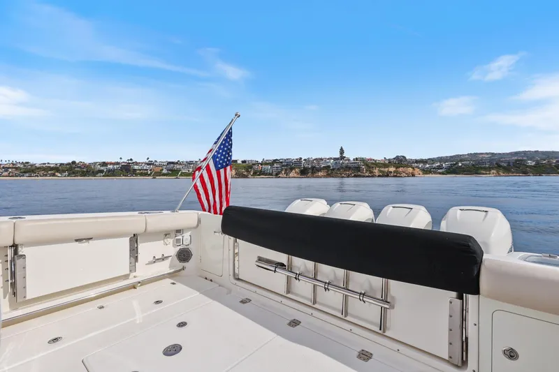 Slide: The Image of 2018 Boston Whaler 420 Outrage boat with American flag, coastal view in background. - 61