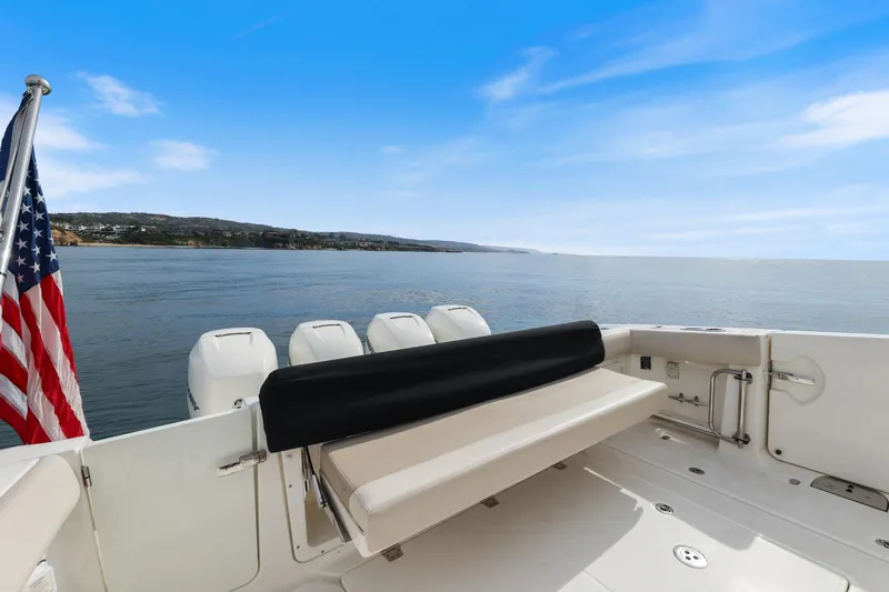 Slide: The Image of 2018 Boston Whaler 420 Outrage boat with American flag, ocean view, and clear blue sky. - 62