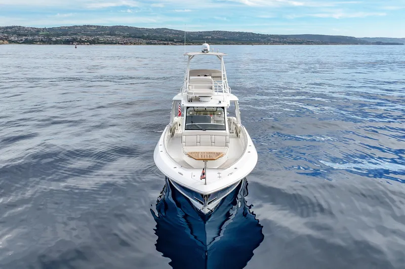 Slide: The Image of 2018 Boston Whaler 420 Outrage on calm ocean waters with scenic coastline backdrop. - 7