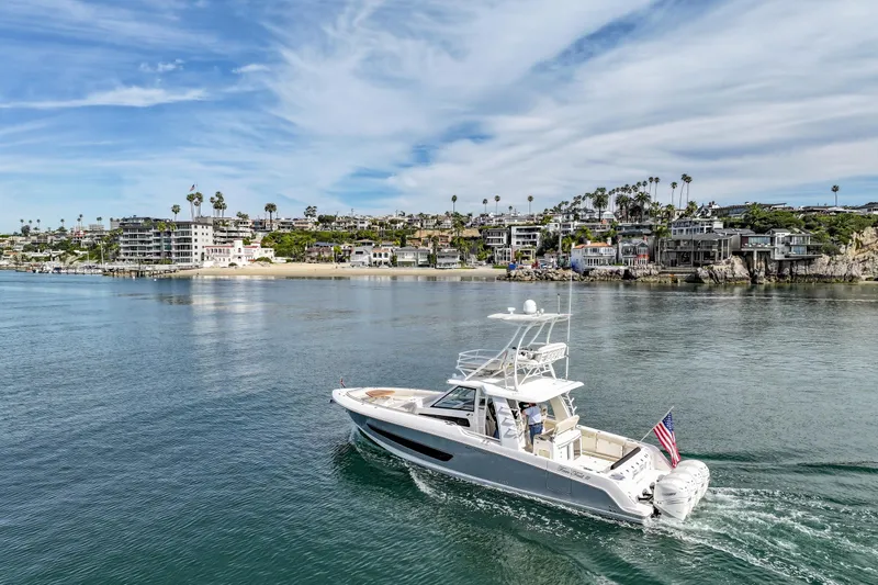 Slide: The Image of 2018 Boston Whaler 420 Outrage cruising near coastal homes under a blue sky. - 81