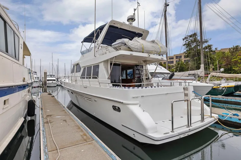 Slide: The Image of Luxury Symbol 58 yacht docked at marina, 2002 model, clear sky background. - 2