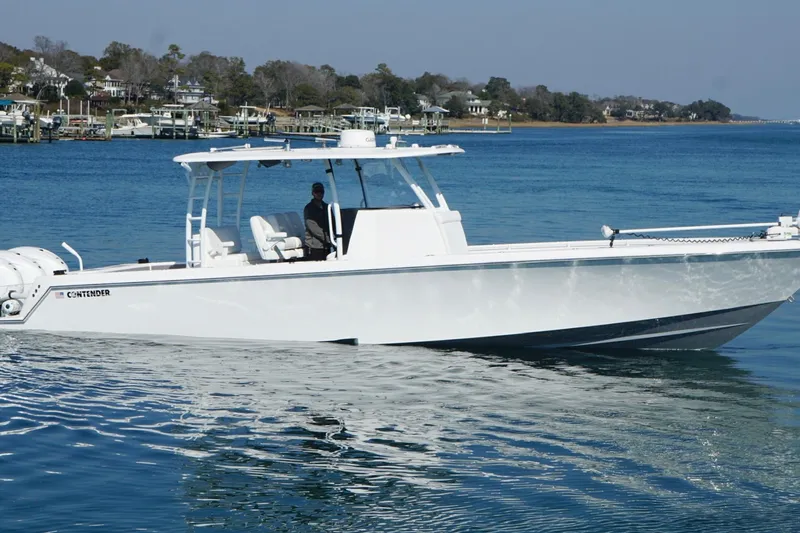 The Image of 2024 Contender 39 ST boat cruising on calm blue waters near a coastal town. - 1