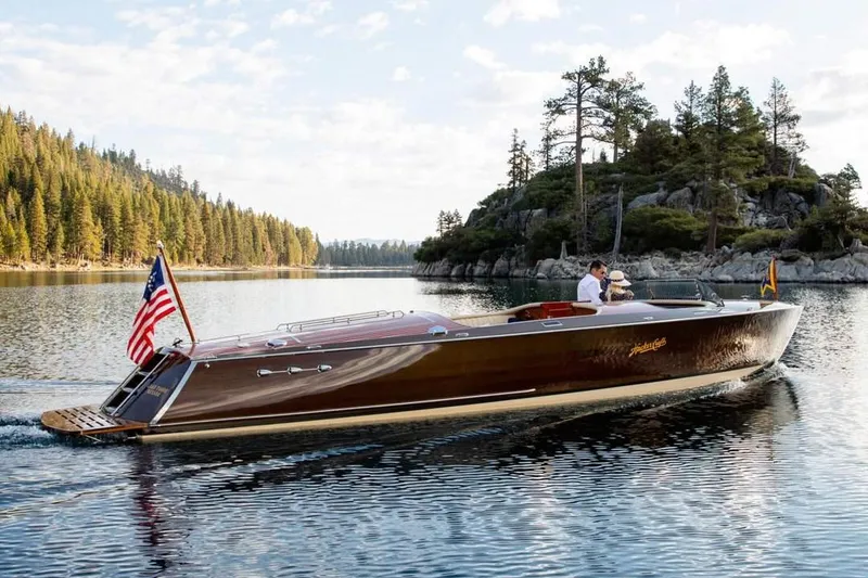 Slide: The Image of 2007 Hacker-Craft 32 Sportabout boat cruising on a serene lake with scenic forest backdrop. - 0