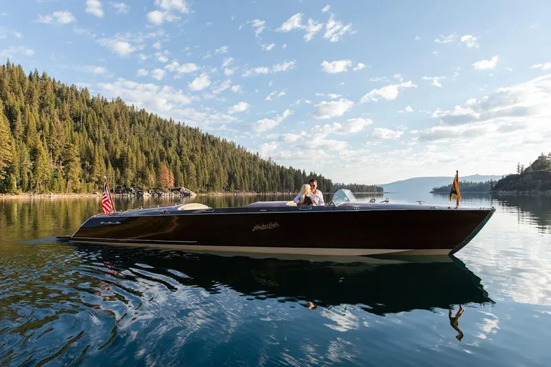 Slide: The Image of 2007 Hacker-Craft 32 Sportabout boat cruising on a serene lake with forested shoreline. - 5