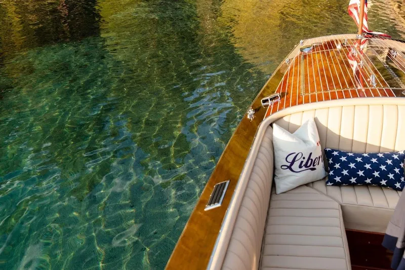 Slide: The Image of Luxurious 2007 Hacker-Craft 32 Sportabout boat on clear water, featuring elegant seating and decorative pillows. - 8