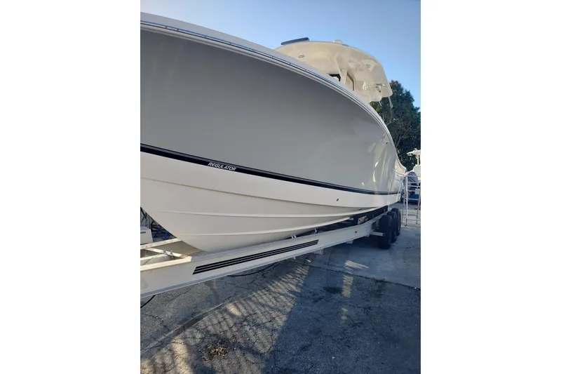 Slide: The Image of 2022 Regulator 31 boat on trailer, sleek design, white hull, outdoor setting. - 17