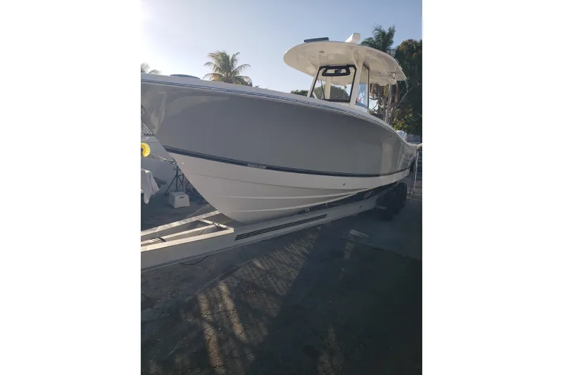 Slide: The Image of 2022 Regulator 31 boat on trailer, side view with palm trees in background. - 18