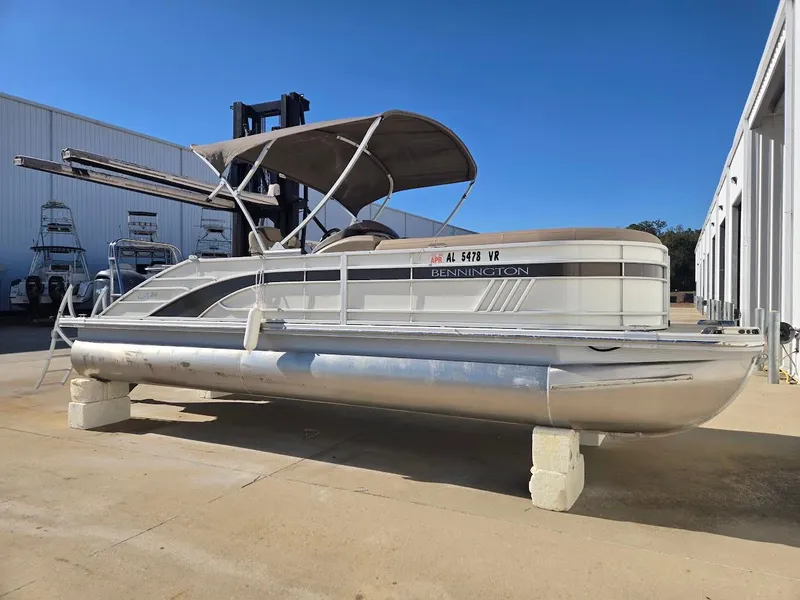Slide: The Image of 2021 Bennington LX24SBSD pontoon boat on a parking lot. - 2