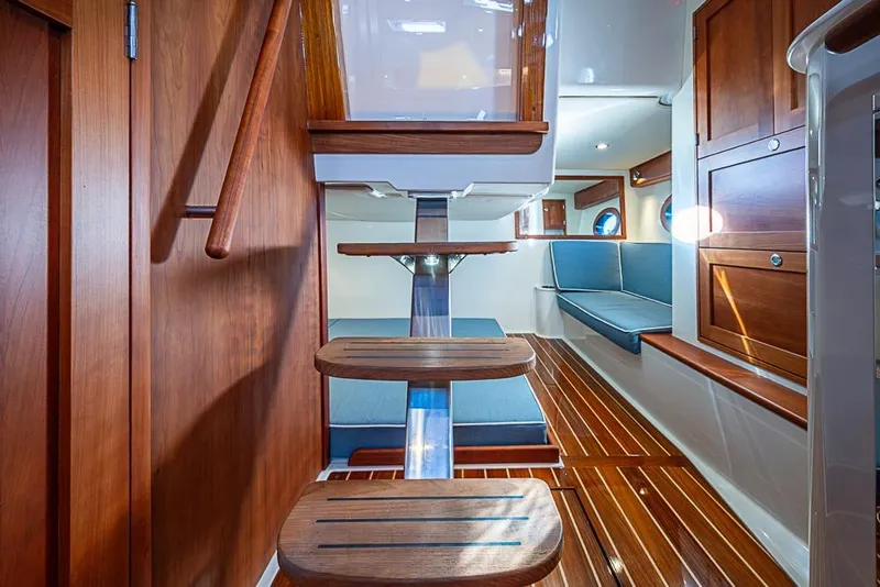 Slide: The Image of 2023 Hinckley Sport Boat 40 X interior with wooden finishes and blue seating. - 22
