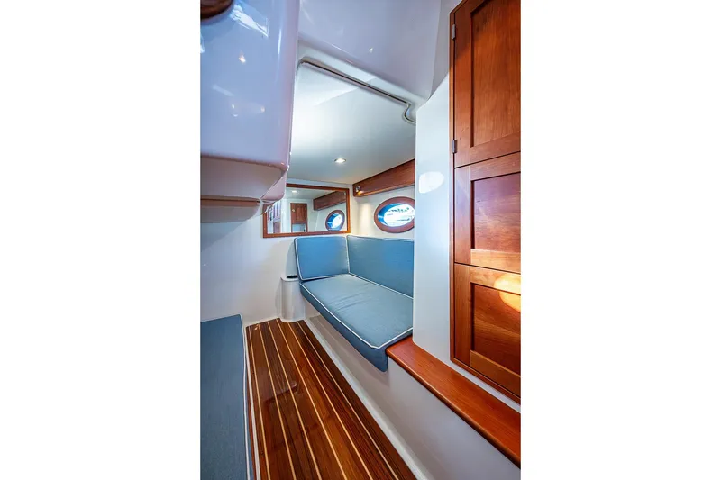 Slide: The Image of Interior of 2023 Hinckley Sport Boat 40 X with wooden cabinetry and blue seating. - 26