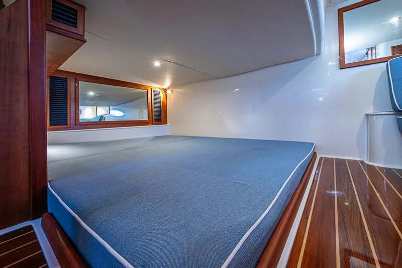 Slide: The Image of 2023 Hinckley Sport Boat 40 X cabin interior with blue bedding and wooden accents. - 32