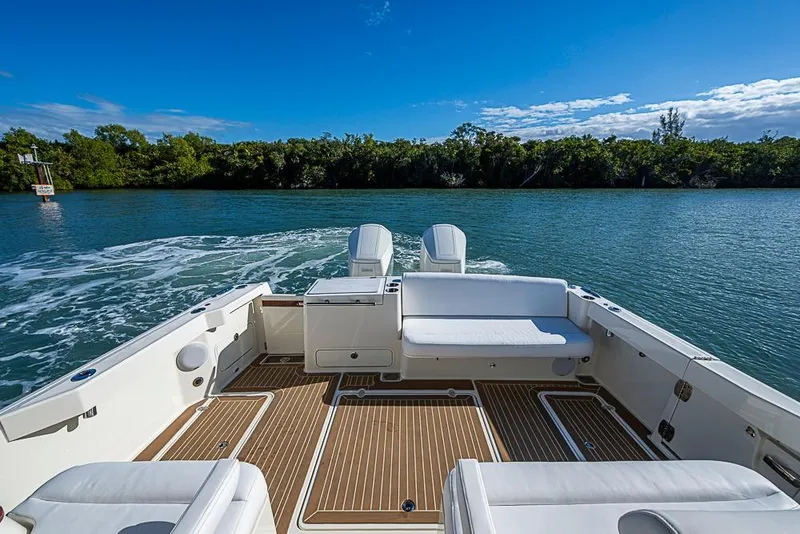 Slide: The Image of 2023 Hinckley Sport Boat 40 X cruising on a serene waterway under a clear blue sky. - 6