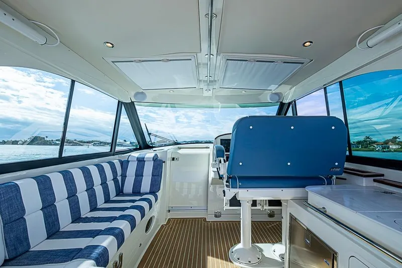 Slide: The Image of Interior of 2023 Hinckley Sport Boat 40 X with striped seating and blue captain's chair. - 18