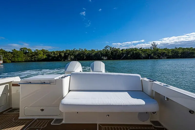 Slide: The Image of 2023 Hinckley Sport Boat 40 X, rear seating, scenic water view, clear blue sky. - 7
