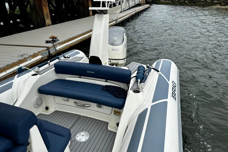 Slide: The Image of 2022 Brig Eagle 8 boat docked, featuring blue seating and Suzuki outboard motor. - 14