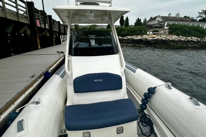 Slide: The Image of 2022 Brig Eagle 8 boat docked by a wooden pier, featuring blue seating. - 7