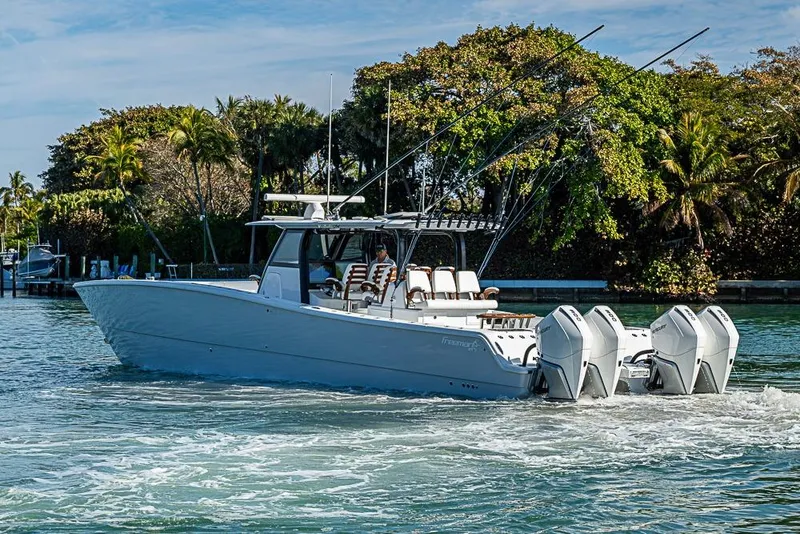 Slide: The Image of 2023 Freeman 47 boat cruising on water with lush greenery in the background. - 11