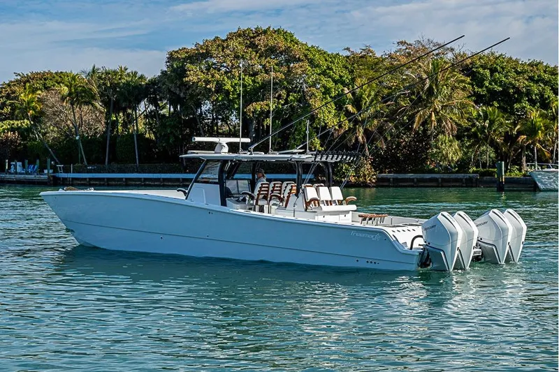 Slide: The Image of 2023 Freeman 47 boat with multiple engines on calm water, surrounded by lush greenery. - 12