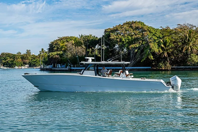 Slide: The Image of 2023 Freeman 47 boat cruising on a serene waterway with lush greenery. - 14