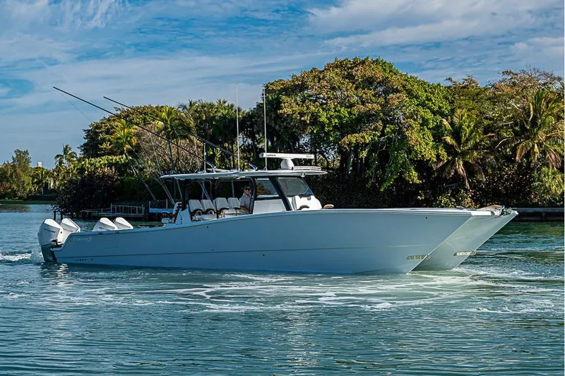 Slide: The Image of 2023 Freeman 47 boat cruising on a scenic waterway with lush greenery. - 2