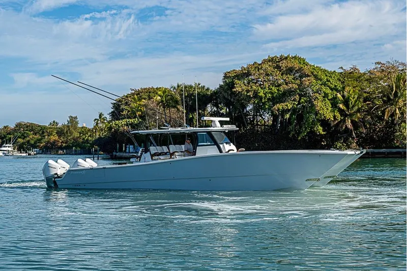 Slide: The Image of 2023 Freeman 47 boat cruising on a sunny day near lush greenery. - 3