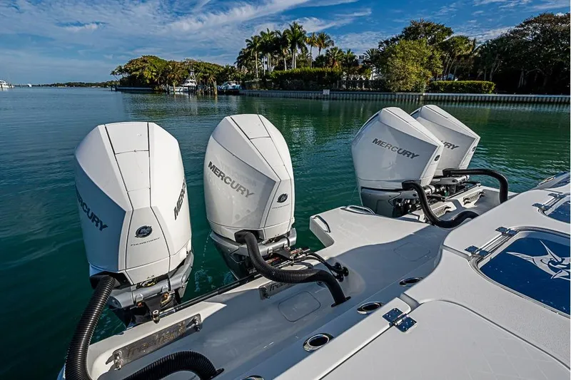 Slide: The Image of Four Mercury outboard engines on a 2023 Freeman 47 boat, docked by lush greenery. - 49