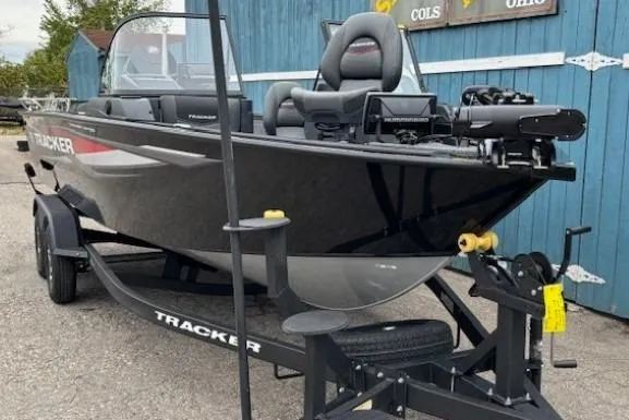 Slide: The Image of 2026 Tracker Targa V-19 Combo boat on trailer, parked near blue building. - 2