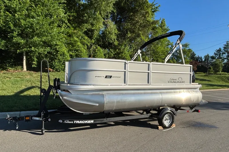 Slide: The Image of 2026 Sun Tracker Party Barge 16 DLX pontoon boat on trailer, parked outdoors. - 1