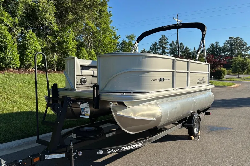 Slide: The Image of 2026 Sun Tracker Party Barge 16 DLX pontoon boat on trailer, parked outdoors. - 2