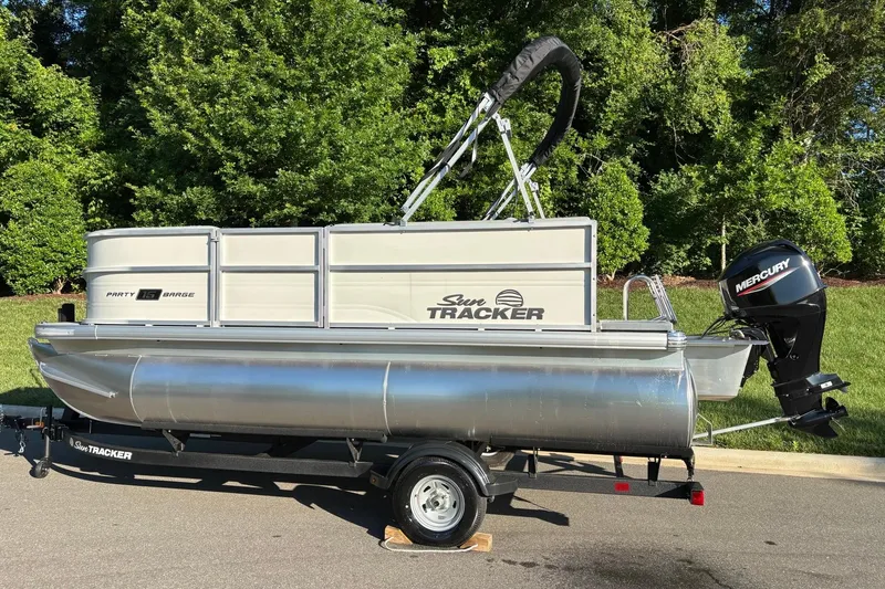 Slide: The Image of 2026 Sun Tracker Party Barge 16 DLX pontoon boat on trailer, parked outdoors. - 3