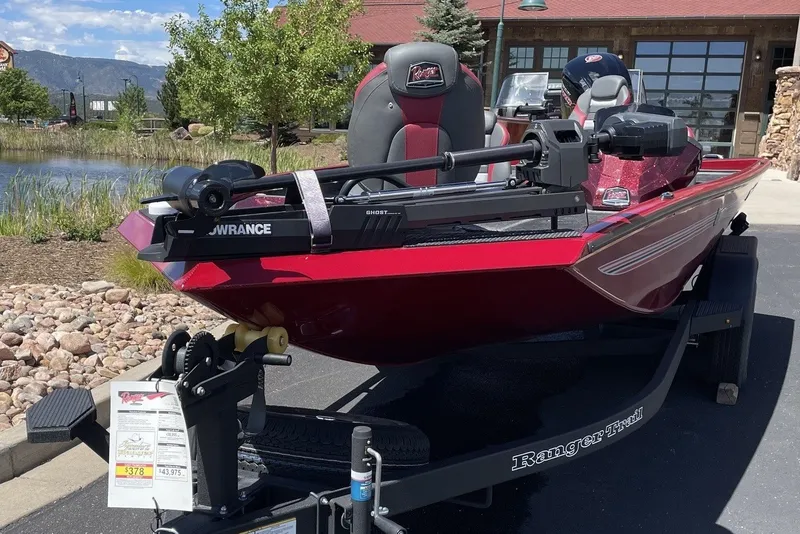 Slide: The Image of 2026 Ranger RT188P boat in red on a trailer, parked near a pond. - 1