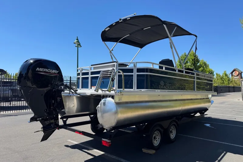 Slide: The Image of 2026 Sun Tracker SportFish 22 DLX pontoon boat with Mercury engine, parked outdoors. - 4