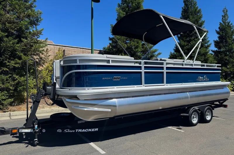 Slide: The Image of 2026 Sun Tracker SportFish 22 DLX pontoon boat on trailer, parked outdoors. - 3