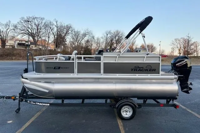 Slide: The Image of 2026 Sun Tracker Bass Buggy 16 XL Select pontoon boat on trailer in parking lot. - 111
