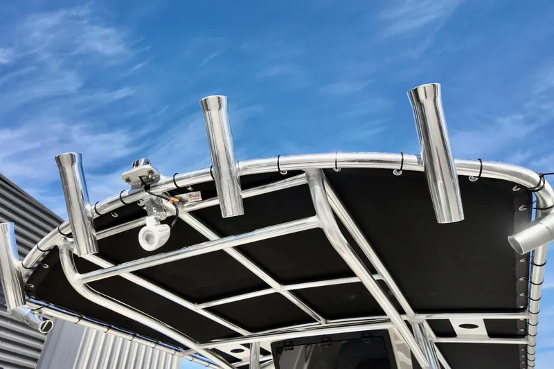 Slide: The Image of 2026 Bulls Bay 230 Center Console boat with rod holders and T-top against blue sky. - 3