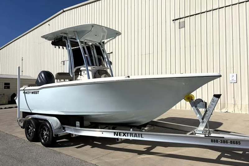 The Image of 2024 Key West 203 FS boat on trailer, parked outside a large building. - 1