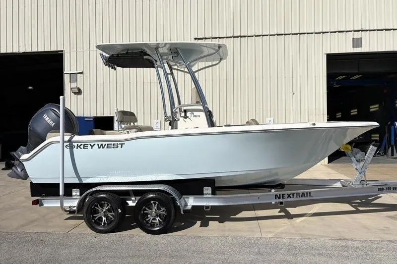 Slide: The Image of 2024 Key West 203 FS boat on trailer, parked outside a building. - 2