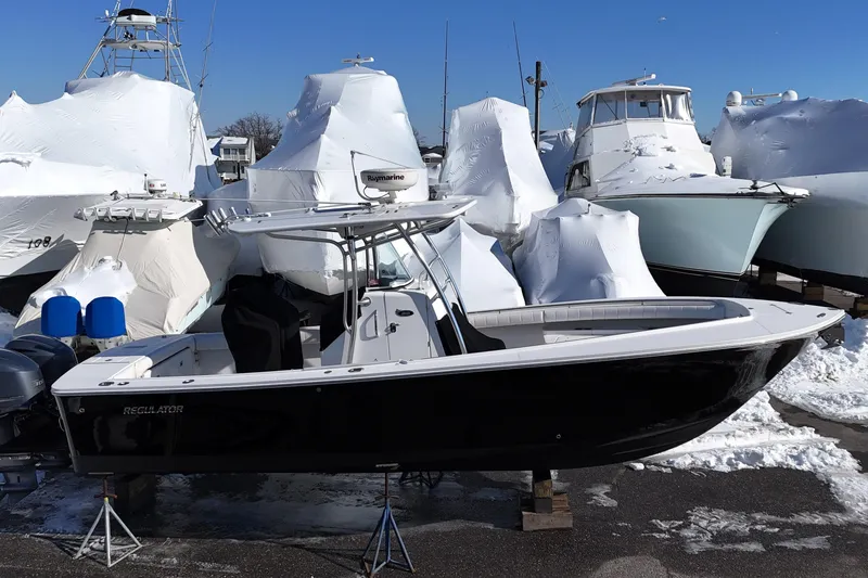 The Image of 2011 Regulator 28 Forward Seating boat in snowy marina, surrounded by covered vessels. - 0