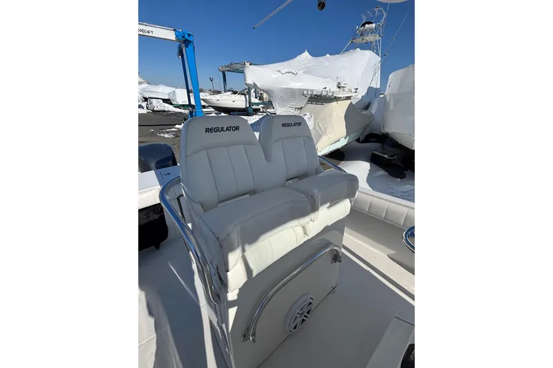 Slide: The Image of 2011 Regulator 28 Forward Seating boat with white cushioned seats and outdoor storage. - 17